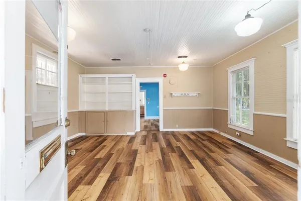 a view of empty room with wooden floor and fan
