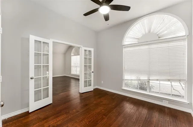an empty room with wooden floor fan and windows
