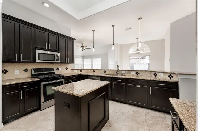 a kitchen with stainless steel appliances granite countertop a sink stove and microwave