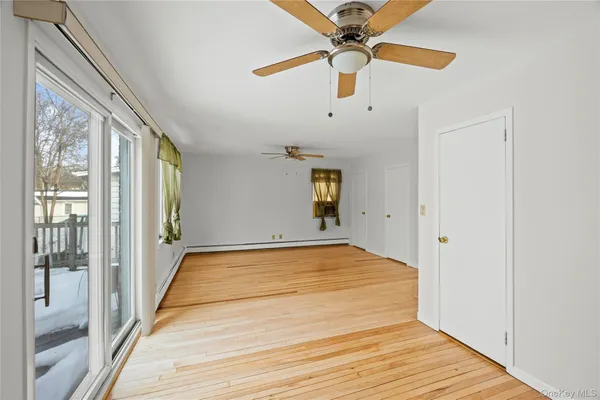a view of an empty room with a window and wooden floor