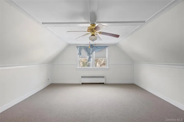 an empty room with a chandelier fan and windows