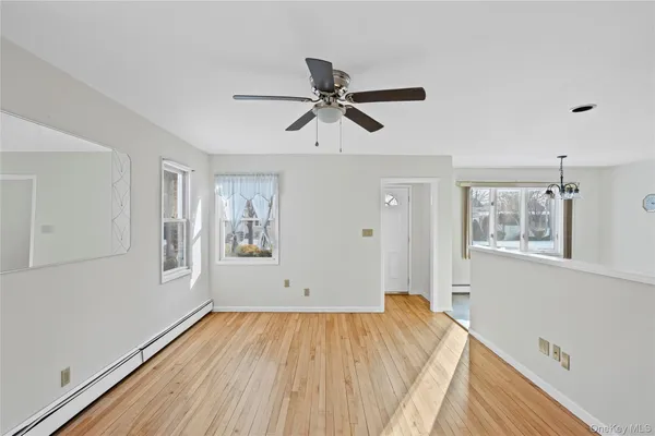 a view of empty room with wooden floor and fan