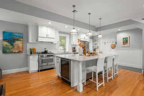 a kitchen with stainless steel appliances granite countertop a stove a sink a refrigerator dining table and chairs with wooden floor