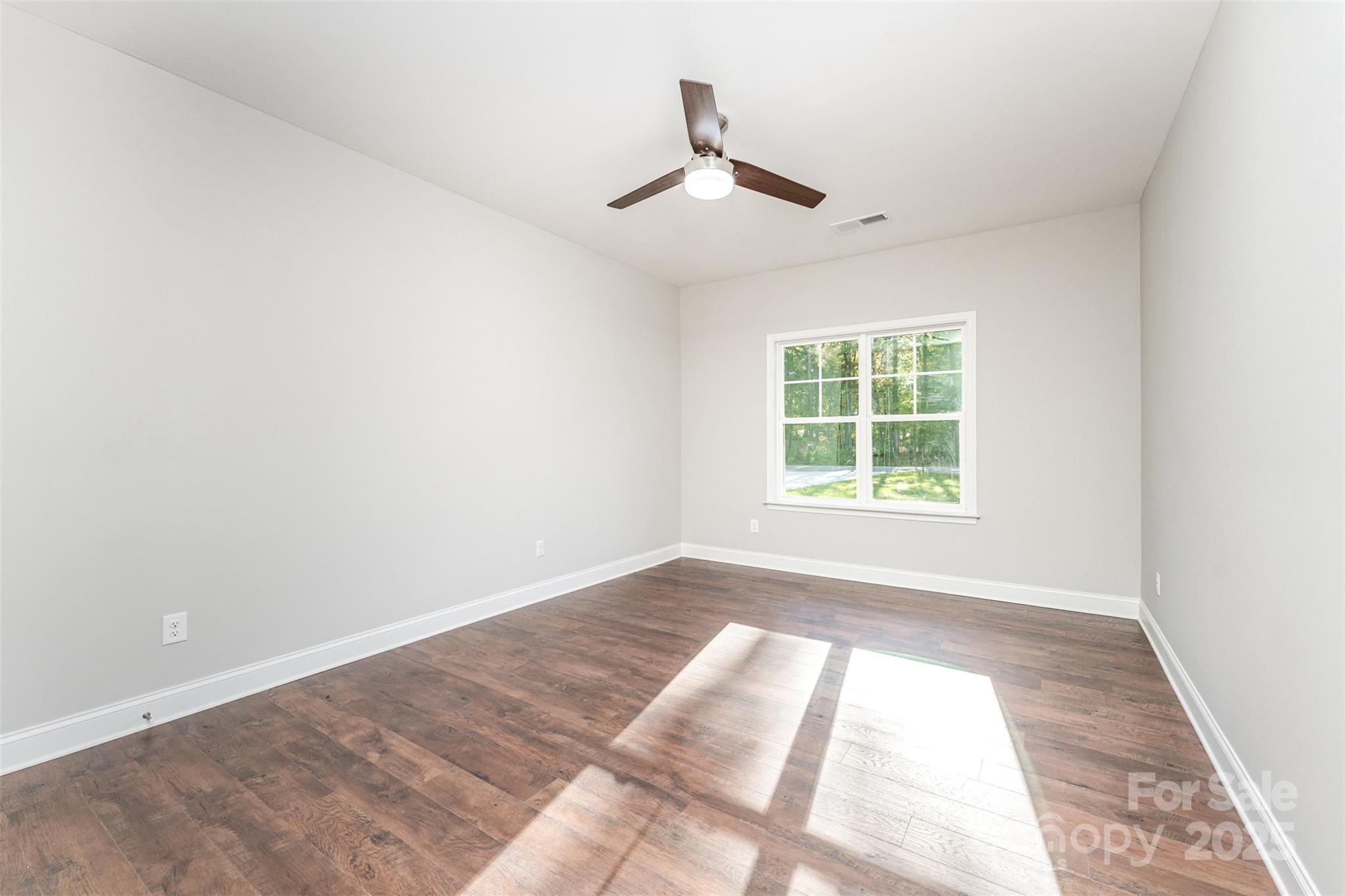 839 Stanley Spencer Mountain Road Gastonia, NC 28056 - Photo 20 of 26 an empty room with wooden floor ceiling fan and windows