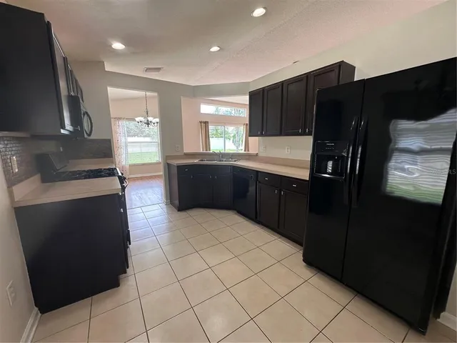 a large kitchen with granite countertop a refrigerator and a stove top oven