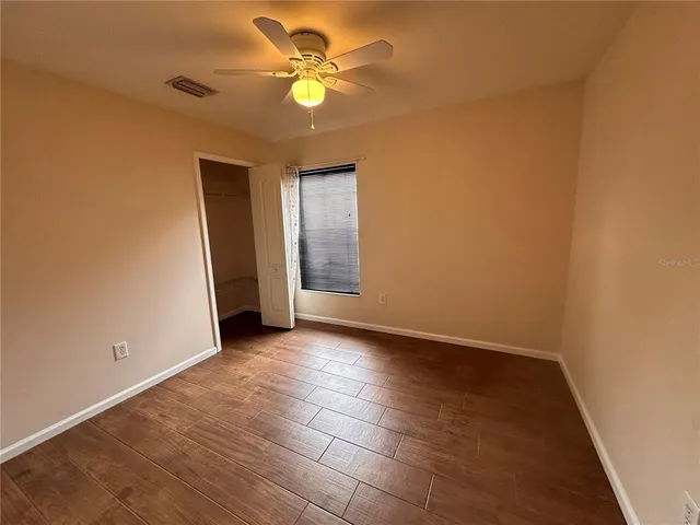 an empty room with a ceiling fan and window