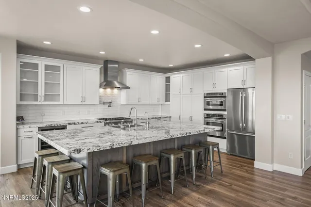 a kitchen with a dining table chairs cabinets wooden floor and appliances