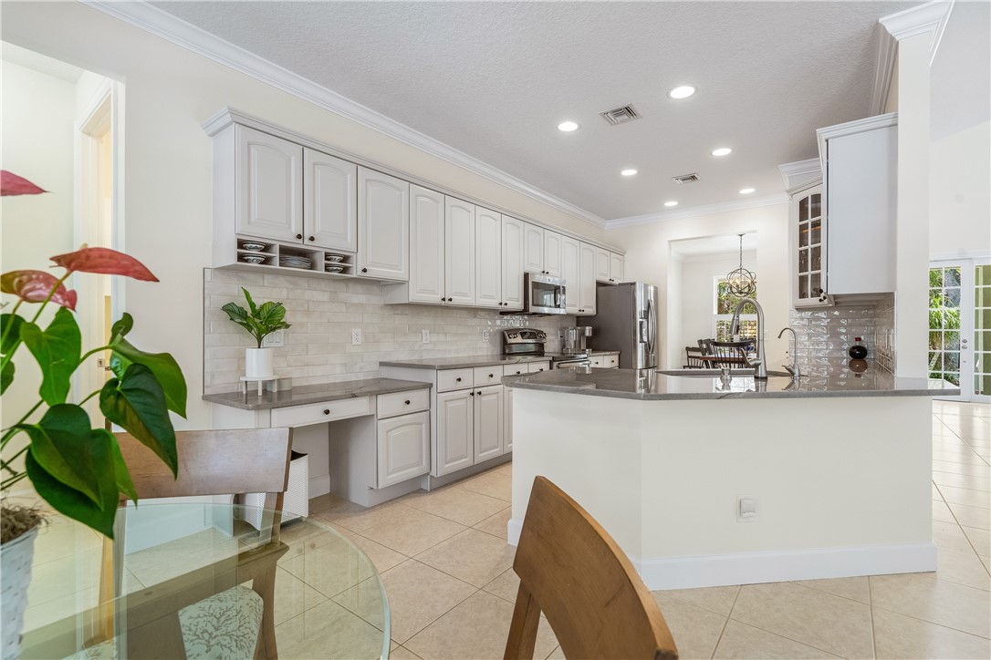 886 Carolina Circle Southwest Vero Beach, FL 32962 - Photo 11 of 36 a kitchen with stainless steel appliances granite countertop sink a refrigerator and white cabinets