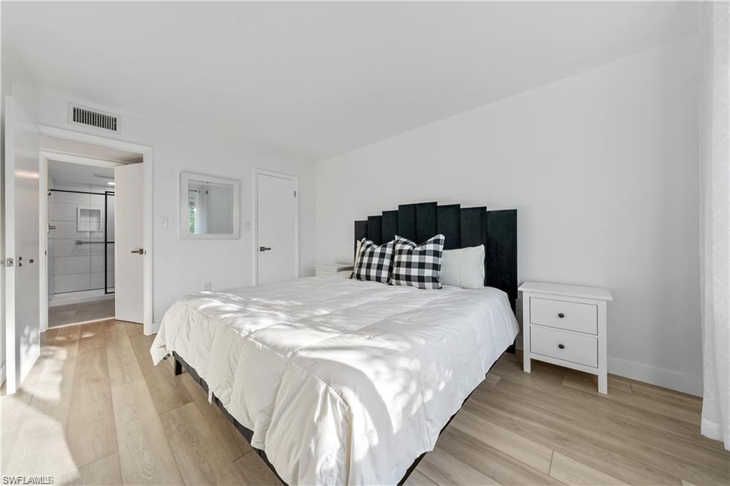 72 7th Street South, Unit 310 Naples, FL 34102 - Photo 18 of 24 a large bed sitting in a bedroom and a bathroom
