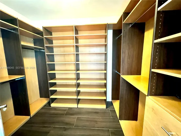 a view of walk in closet with wooden floor and chair