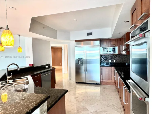 a kitchen with granite countertop a refrigerator a stove and a sink