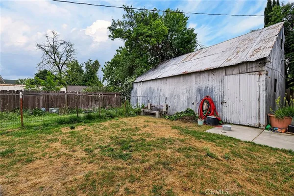 a white house with a big yard plants and large trees