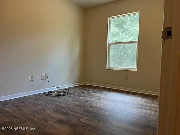an empty room with wooden floor and windows