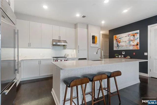 a kitchen with stainless steel appliances granite countertop a stove a refrigerator a white table and chairs