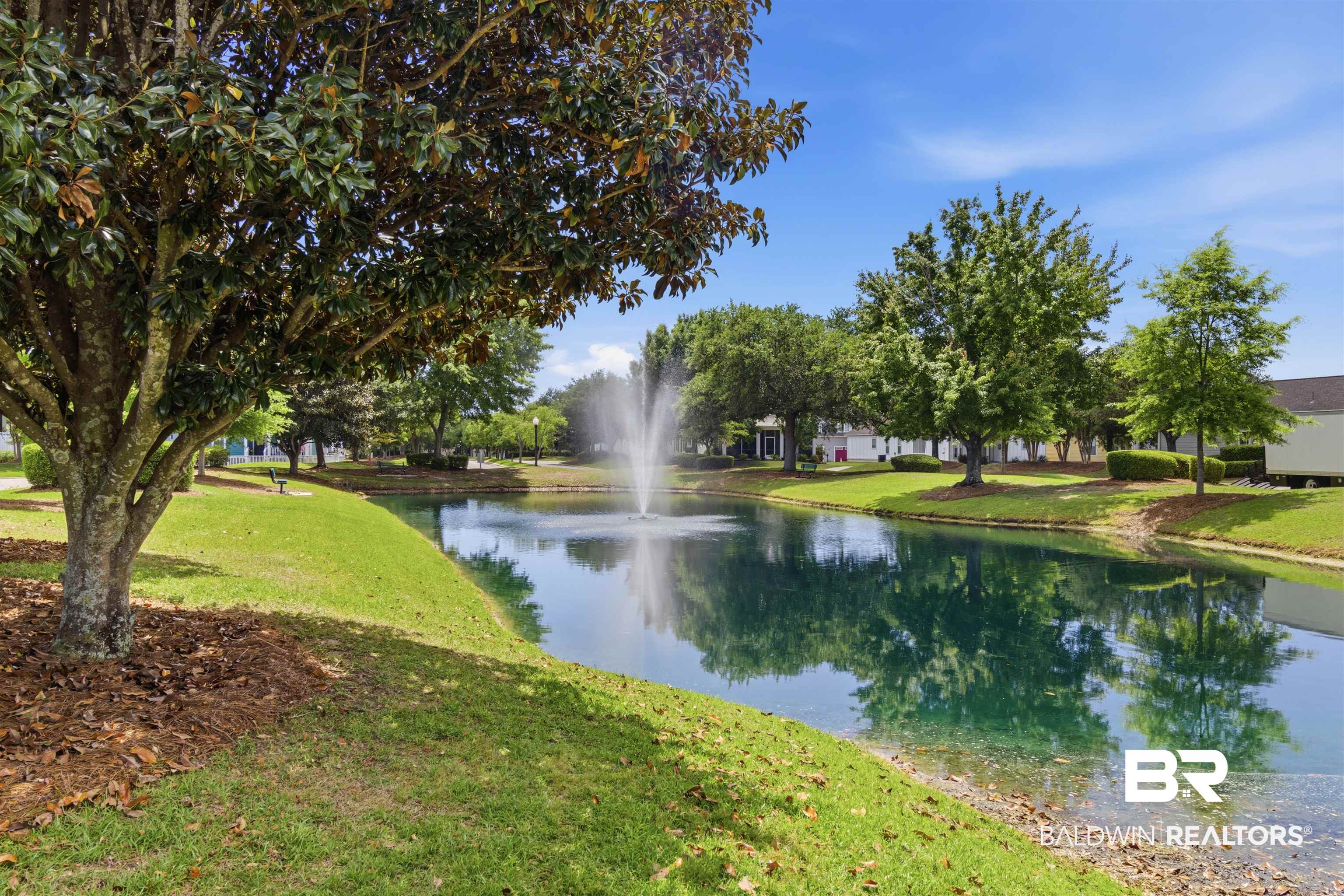 927 Periwinkle Lane Foley, AL 36535 - Photo 20 of 26 Lush green landscaping bordering a tranquil pond with a central fountain