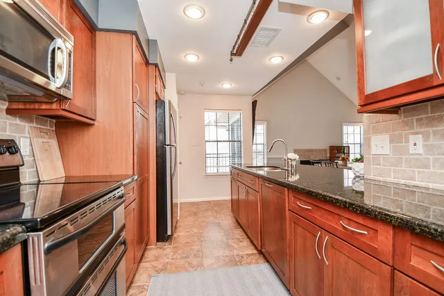 a kitchen with stainless steel appliances granite countertop a sink a stove and a refrigerator