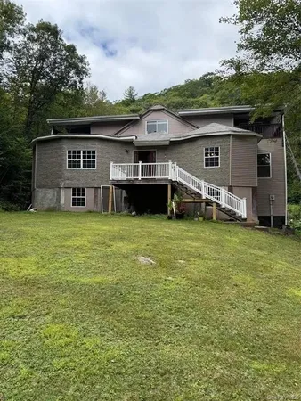 a view of a house with a yard and a large tree