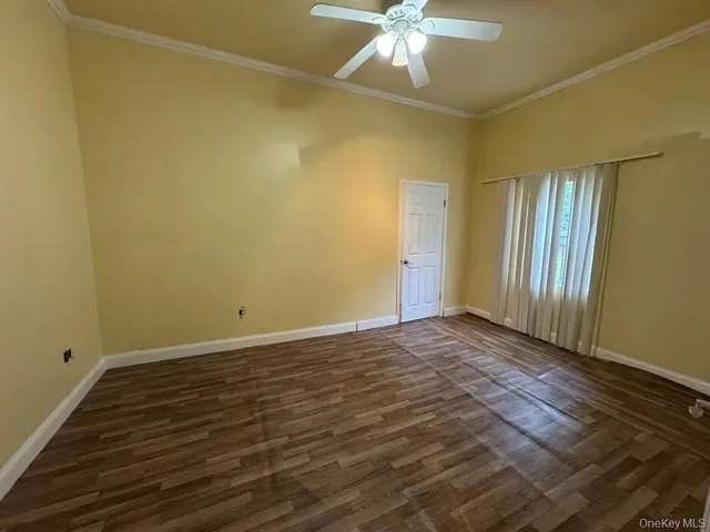 an empty room with wooden floor and fan