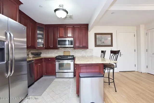 a kitchen with kitchen island granite countertop wooden cabinets and stainless steel appliances