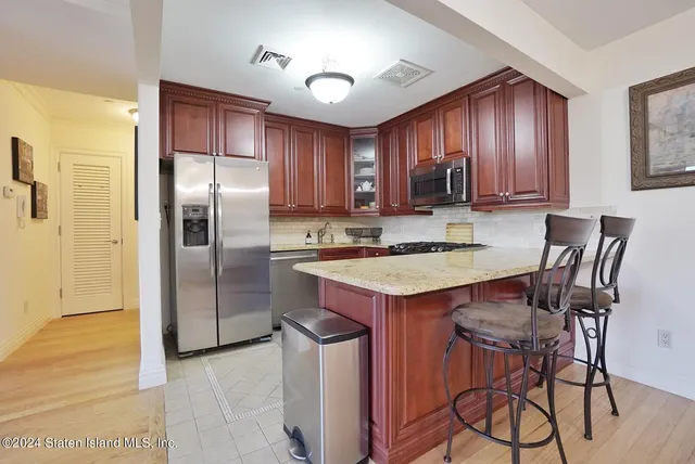 a kitchen with stainless steel appliances granite countertop a refrigerator a stove a sink and chairs