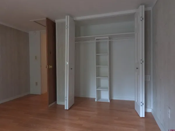 an empty room with wooden floor & closet area