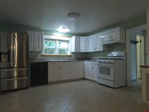 a kitchen with granite countertop white cabinets and stainless steel appliances