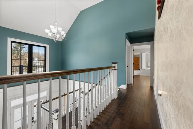 a view of a hallway with wooden floor and chandelier