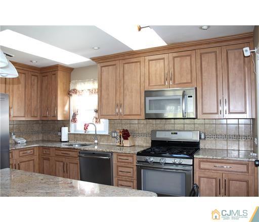20 Dover Road Colonia, NJ 07067 - Photo 5 of 19 a kitchen with kitchen island granite countertop a sink dishwasher stove and cabinets