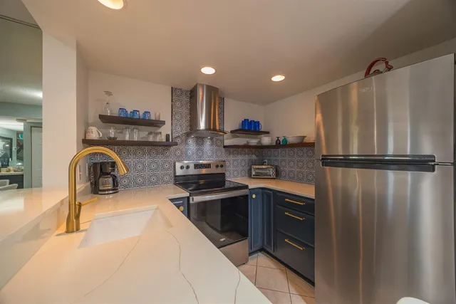 a kitchen with stainless steel appliances granite countertop a refrigerator a sink and a stove