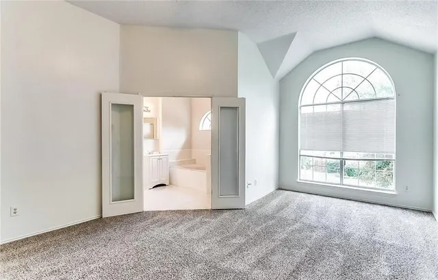 an empty room with large windows and a fireplace