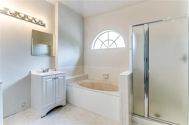 a bathroom with a bathtub a mirror a sink and a window