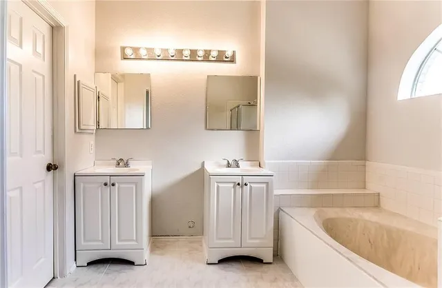 a bathroom with a tub a sink and a window