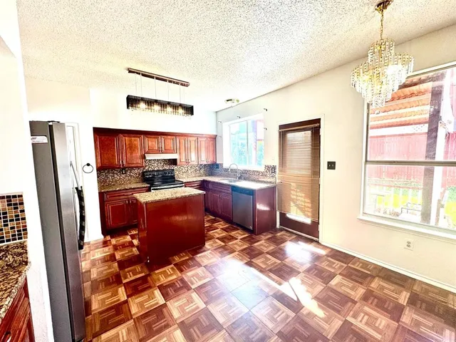 a kitchen with stainless steel appliances granite countertop a refrigerator and a stove top oven