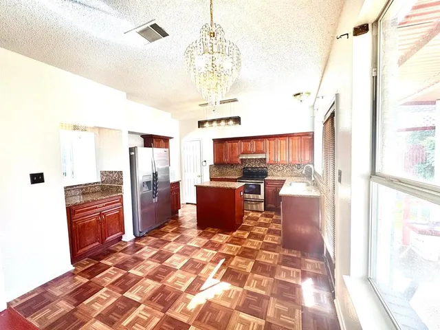 a kitchen with stainless steel appliances kitchen island granite countertop a refrigerator and microwave