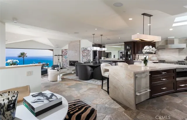 a kitchen with stainless steel appliances granite countertop a sink dishwasher stove refrigerator and couches with wooden floor