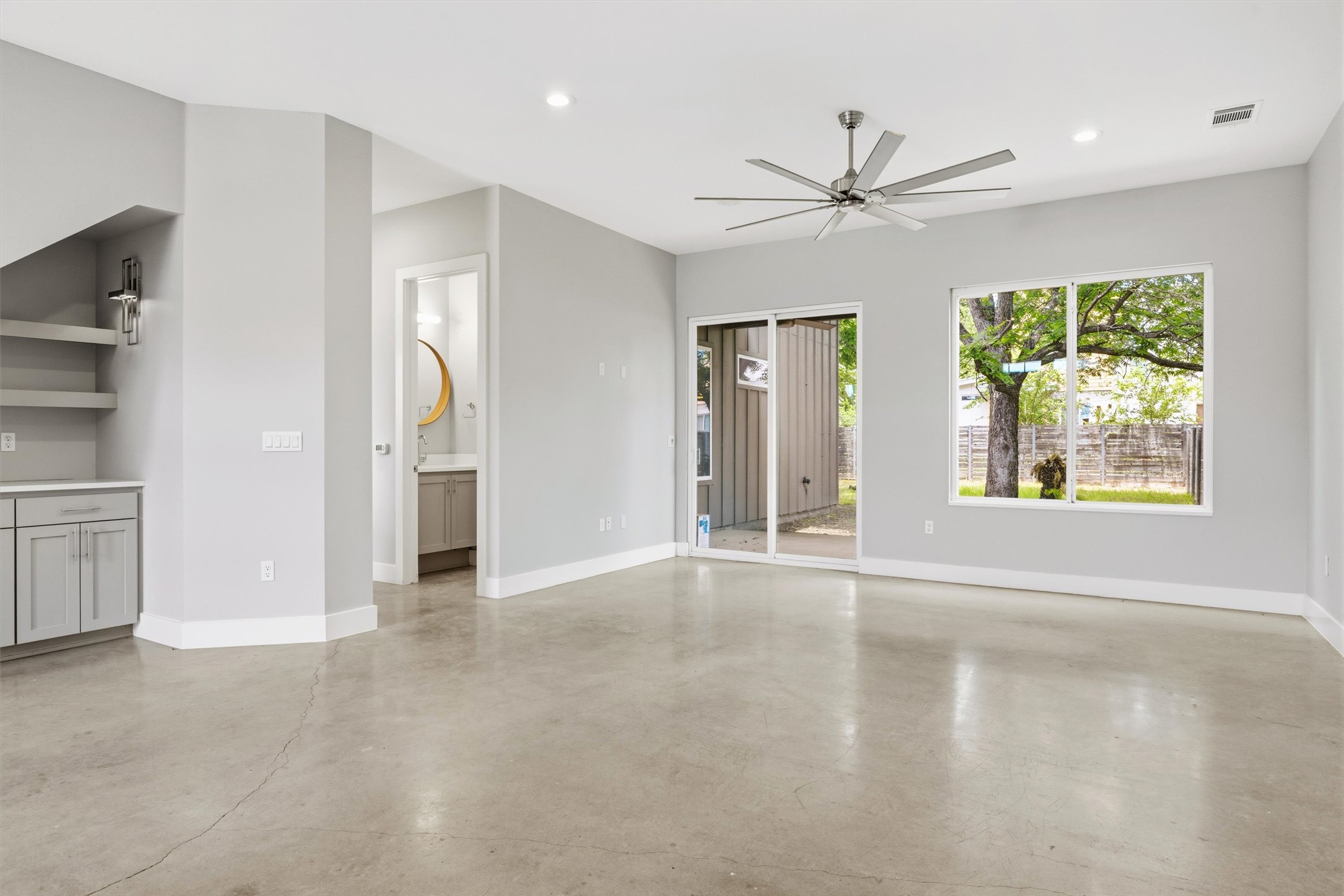 1210 Stobaugh Street, Unit B Austin, TX 78757 - Photo 30 of 40 A well-lit living area features polished concrete flooring and ample natural light through large windows and sliding glass doors.