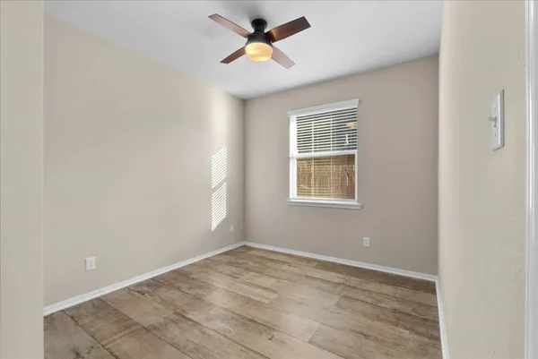 an empty room with a window and a fan