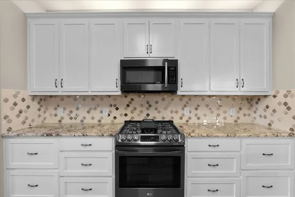 a kitchen with granite countertop white cabinets and stainless steel appliances