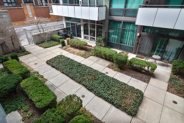 a view of a backyard with plants and a patio with table and chairs potted plants
