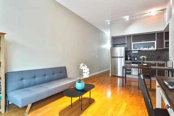 a living room with stainless steel appliances furniture a rug and kitchen view