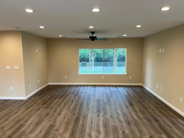 an empty room with wooden floor and windows