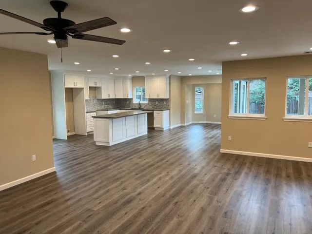 a open kitchen with kitchen island a sink dishwasher stove and wooden floors