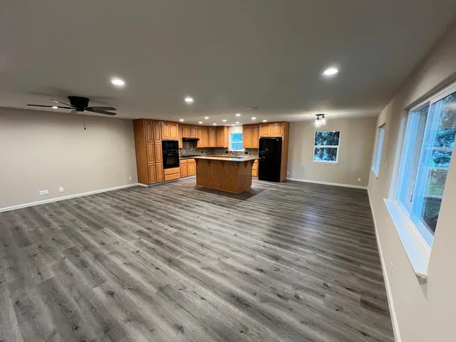 a kitchen with granite countertop a refrigerator a sink dishwasher and wooden cabinets with wooden floor