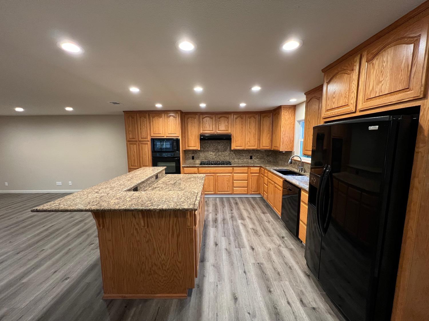 10016 South Priest Road French Camp, CA 95231 - Photo 32 of 63 a kitchen with granite countertop a refrigerator a sink dishwasher and wooden cabinets with wooden floor