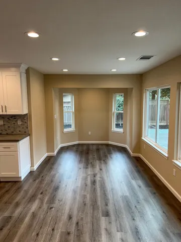 an empty room with wooden floor and windows