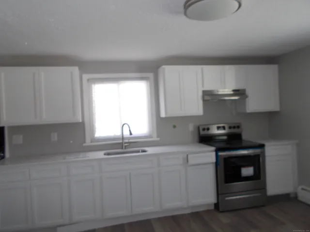 a kitchen with white cabinets appliances a sink and a window