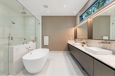 a bathroom with a double vanity sink and mirror with bathtub
