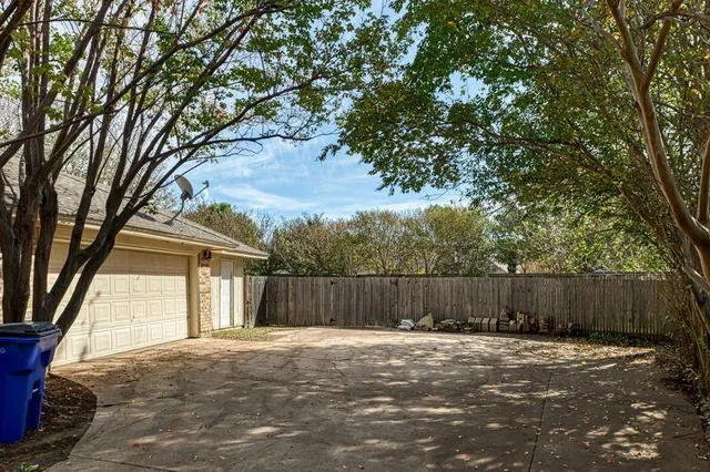 a view of a backyard with large trees and wooden fence