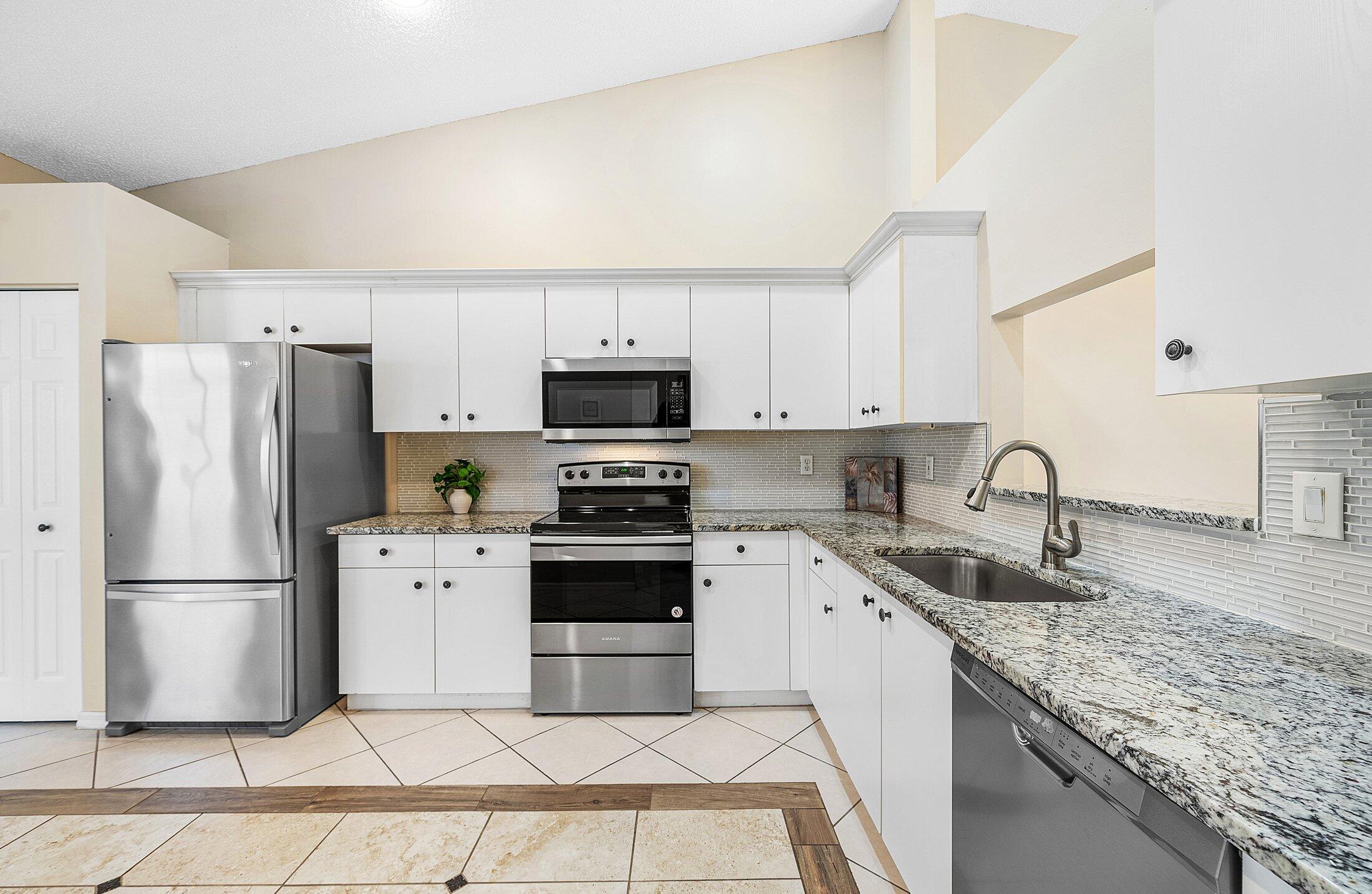 6060 Petunia Road Delray Beach, FL 33484 - Photo 5 of 59 a kitchen with stainless steel appliances granite countertop a refrigerator sink stove microwave and cabinets