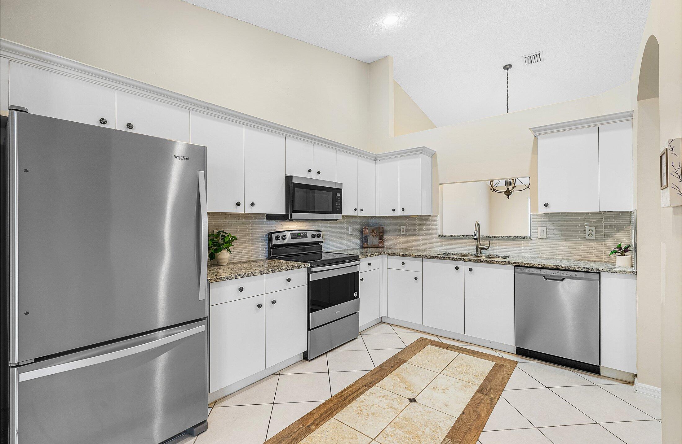 6060 Petunia Road Delray Beach, FL 33484 - Photo 6 of 59 a kitchen with white cabinets and white appliances